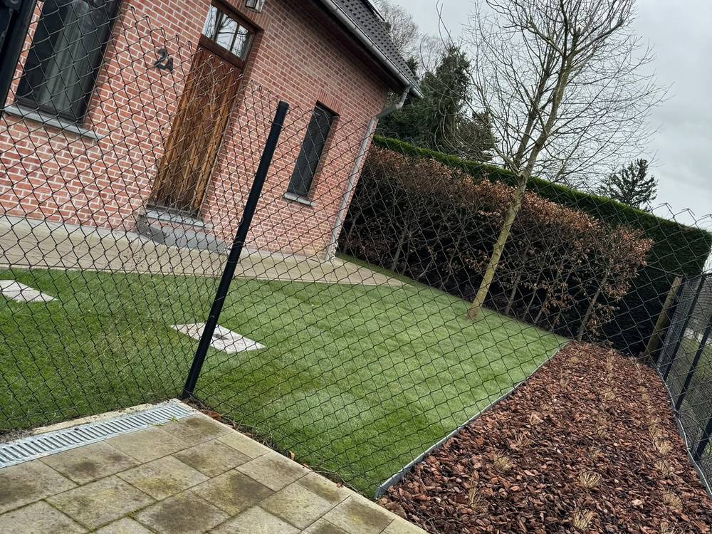 Dezelfde tuin na de werken, met nieuw gras en een border afgewerkt in boomschors.