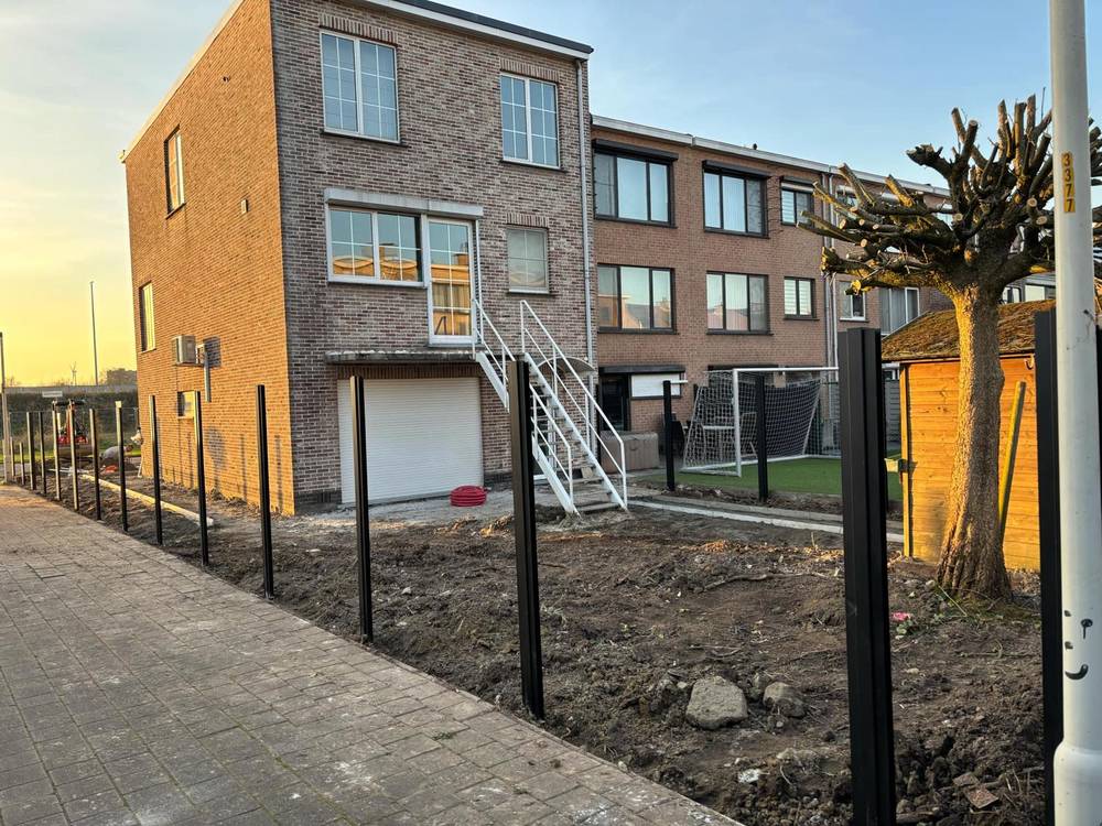 Nieuwbouwwoning tijdens de werken, met net geplaatste afsluitingspalen.