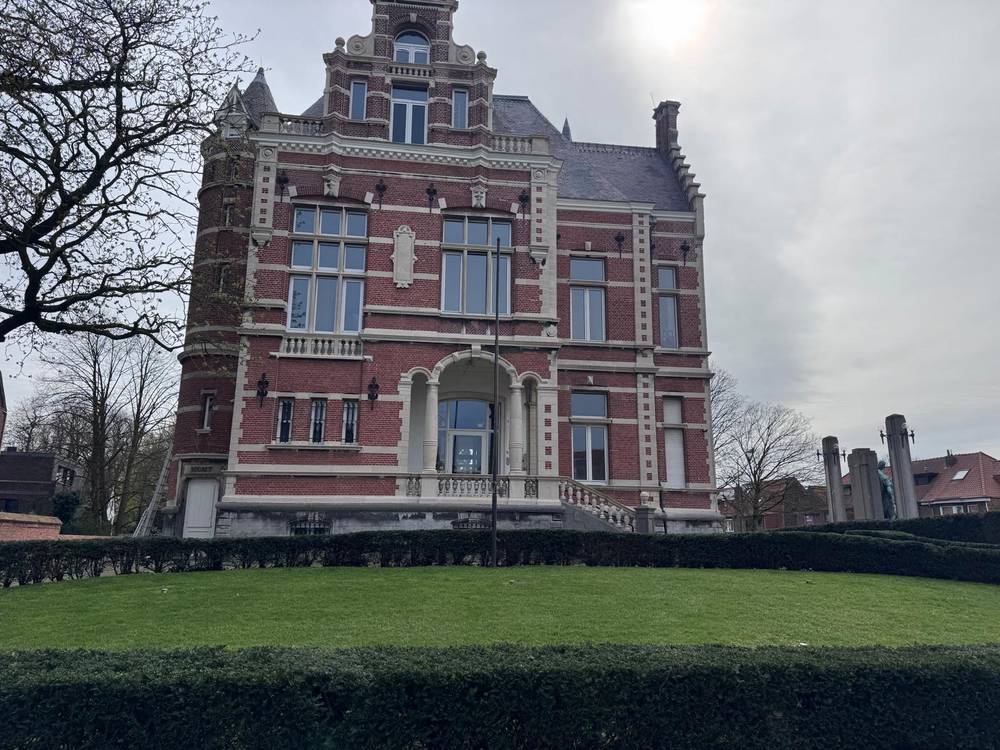 Herenhuis met strak geschoren hagen en een verzorgd gazon ervoor.