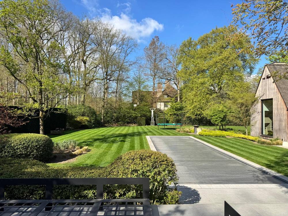 Villatuin met zwembad, gestreept gemaaid gazon en geschoren vormsnoei.